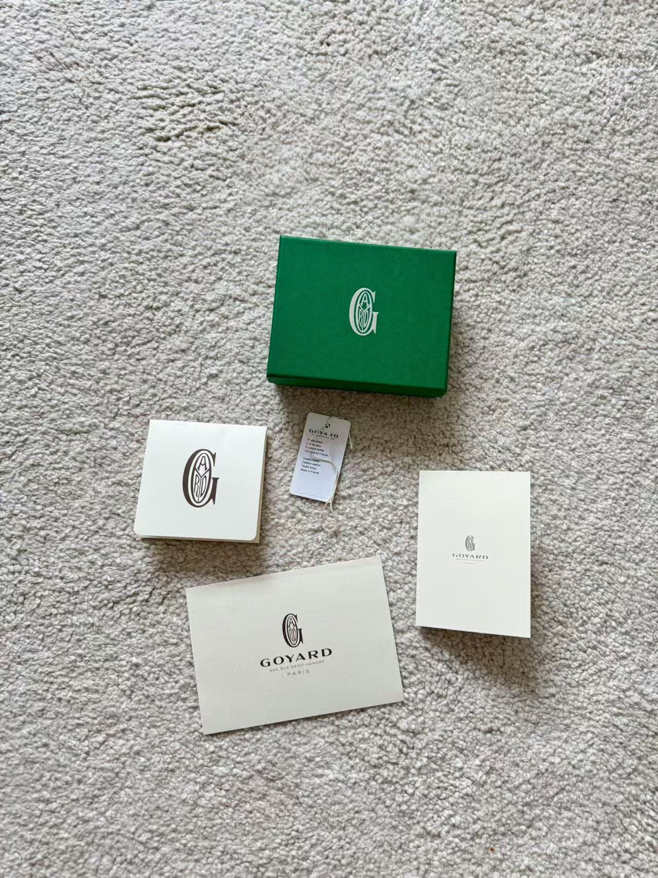 Collection of Goyard packaging items on a textured surface
