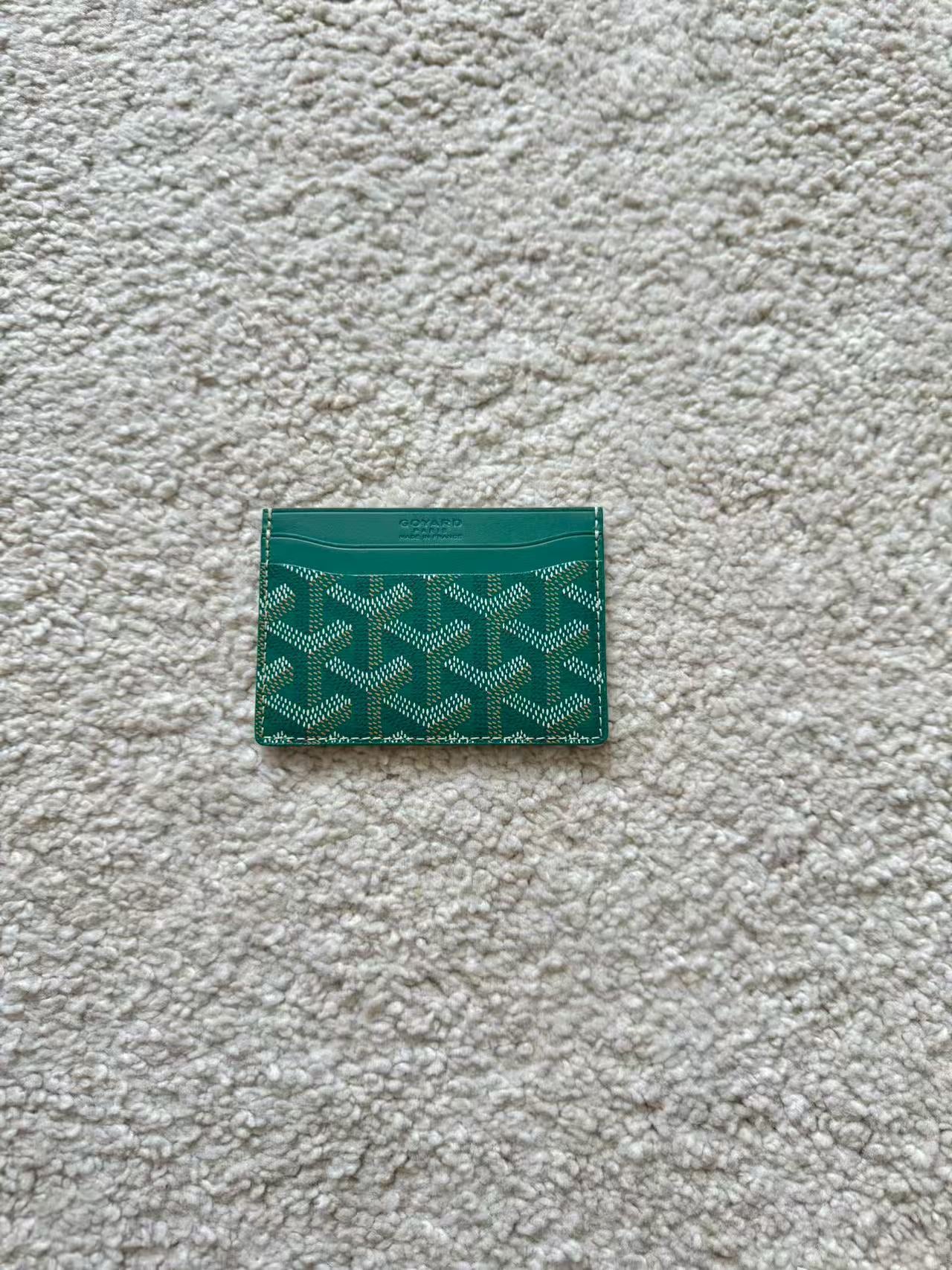 Green cardholder with pattern on a textured gray surface