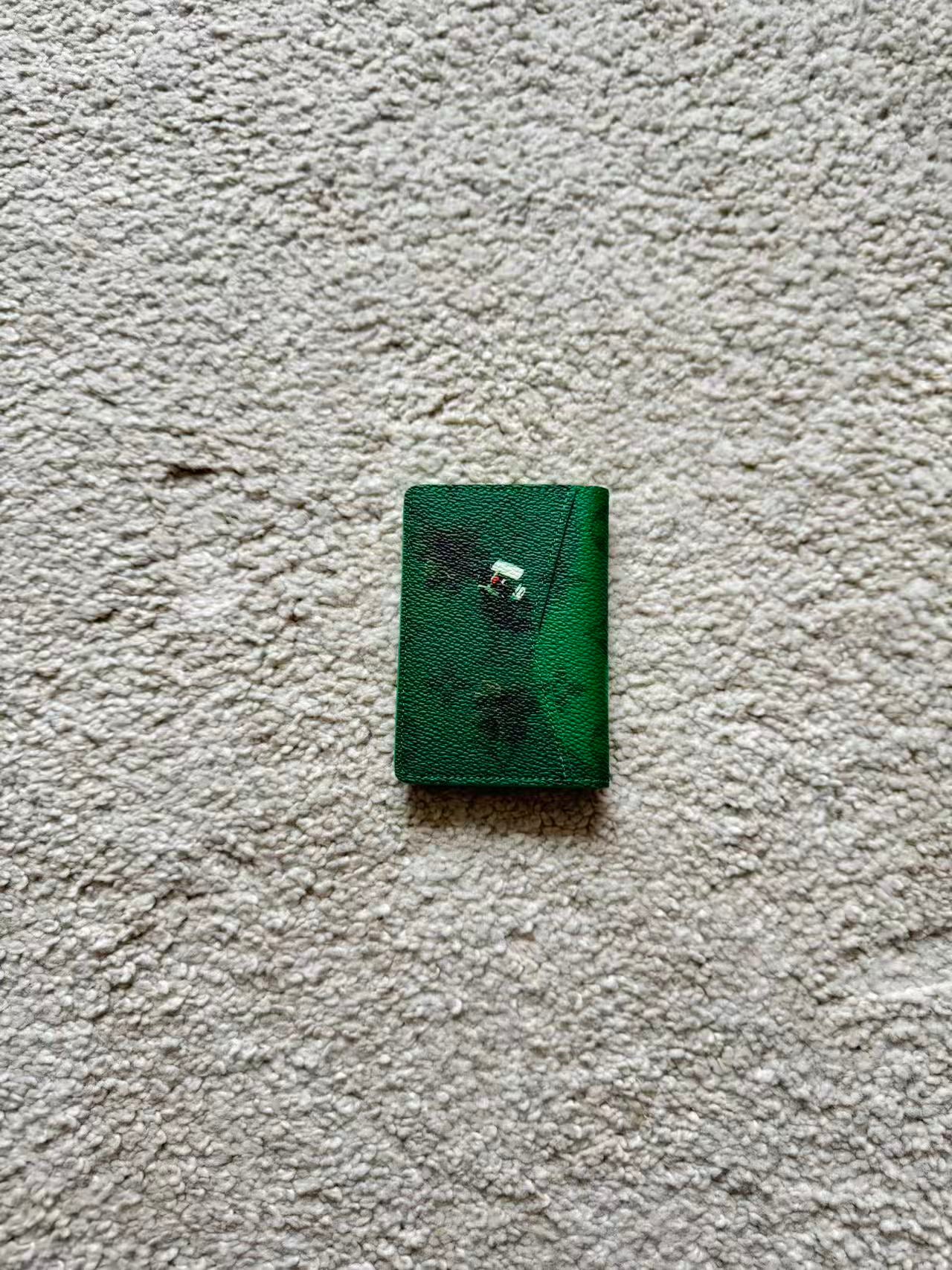 Small green book with floral design on a textured beige surface