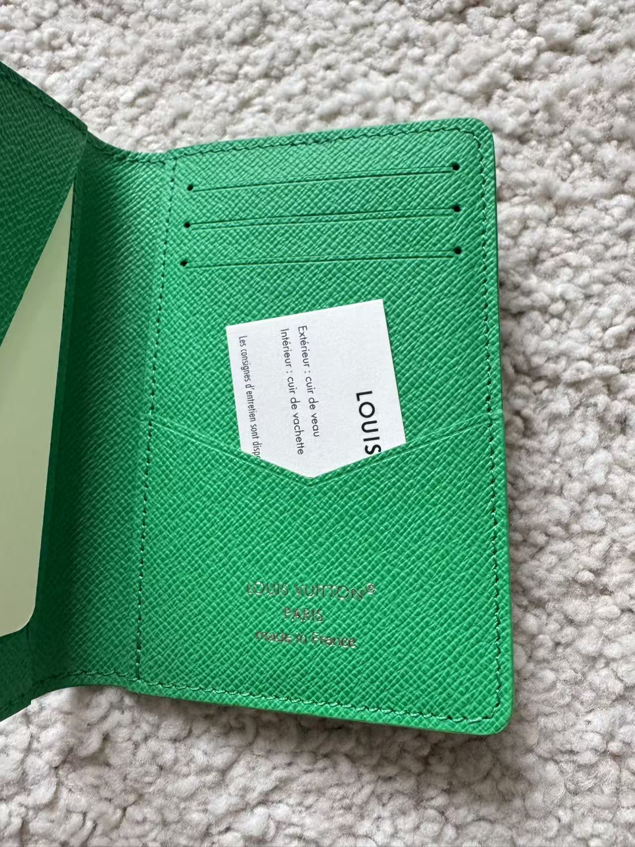 Green wallet with a visible brand label on a textured surface