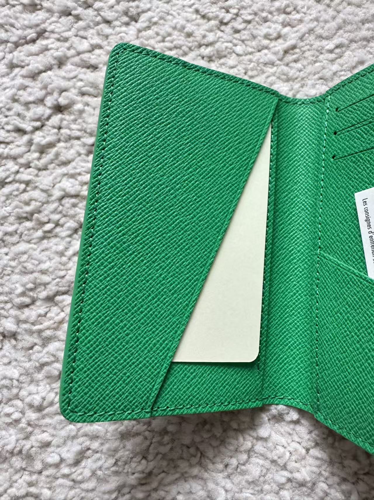 Green textured wallet on a light gray carpet
