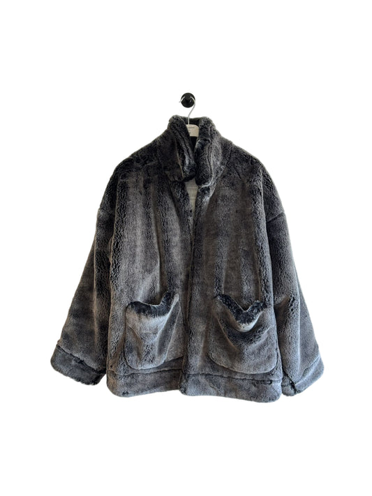 Gray faux fur jacket on a hanger against a white wall