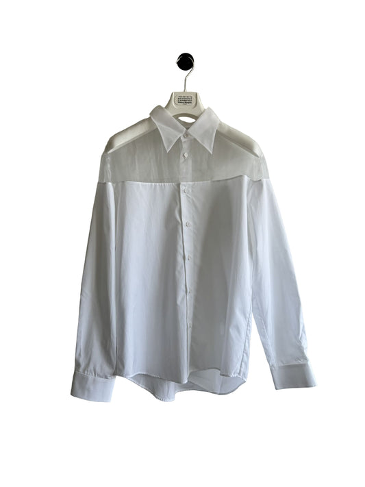 White shirt on a hanger against a plain wall