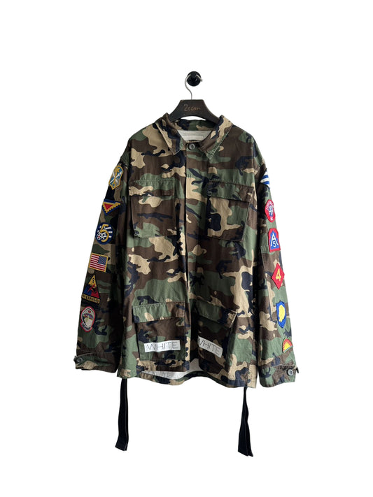 Camouflage jacket with patches on a hanger against a white background