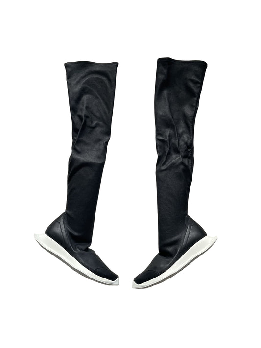 Black knee-high boots on a gray textured surface