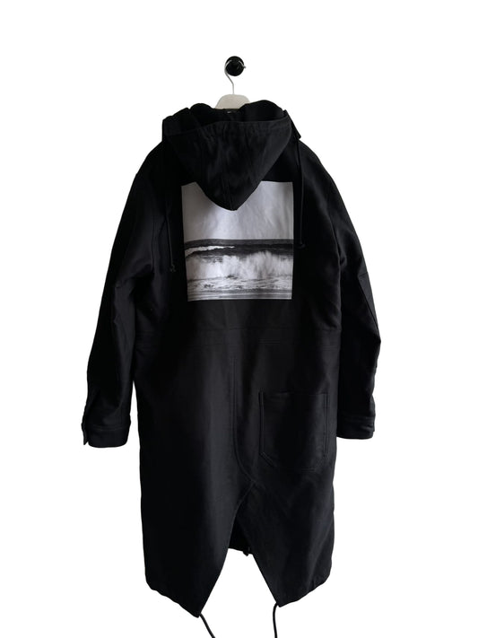 Black hooded coat with a graphic design on a white wall